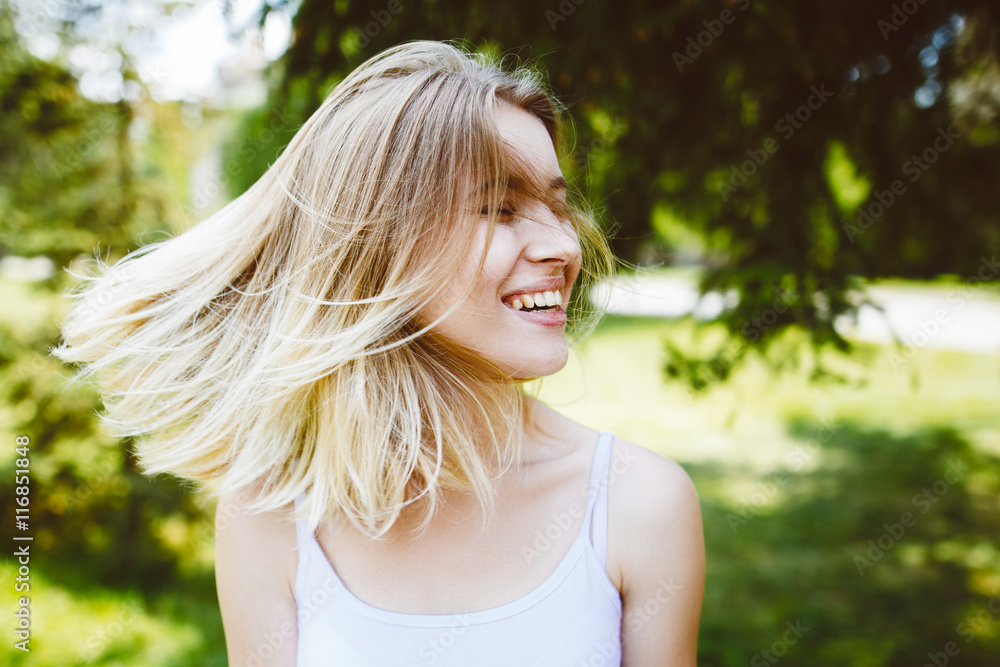 Outdoors portrait of beautiful happy girl with flying hair.Blooming lady's portrait in a s green summer garden