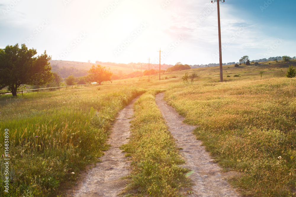 red sunset over green field with road