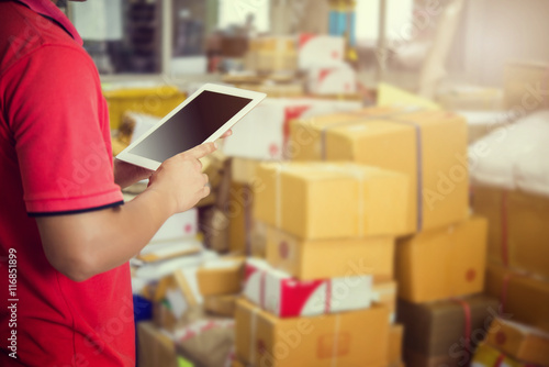 A Man using tablet checking the parcel in warehouse.