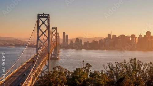 Shot of traffic driving across the Bay Bridge in San Francisco. The buildings of San Francisco can be seen in the distance.
