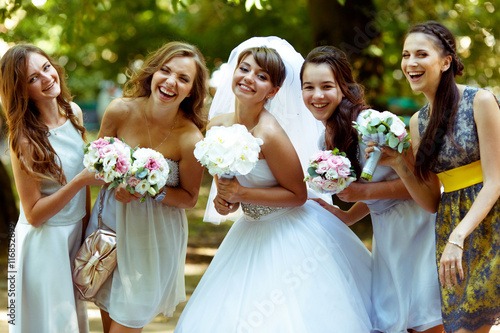 Smiling bride poses with happy bridesmaids with bouqets in their