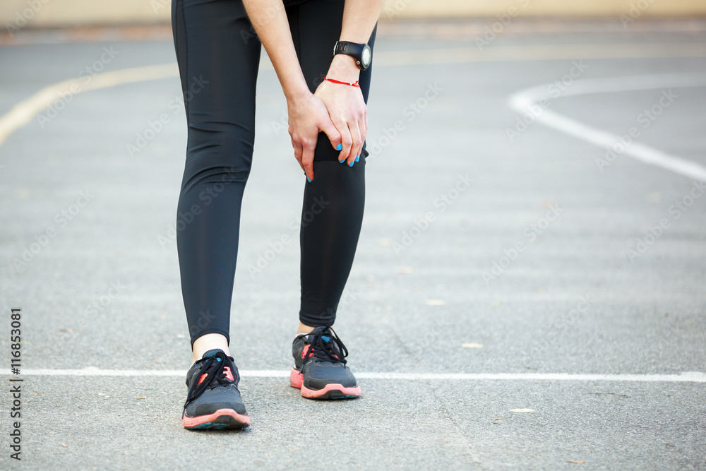 Female runner is holding her injured leg. Female runner is holding her injured leg.