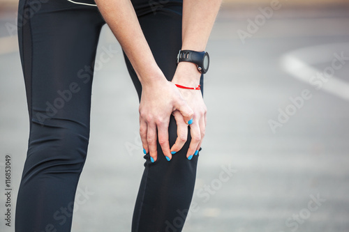 Female runner is holding her injured leg.