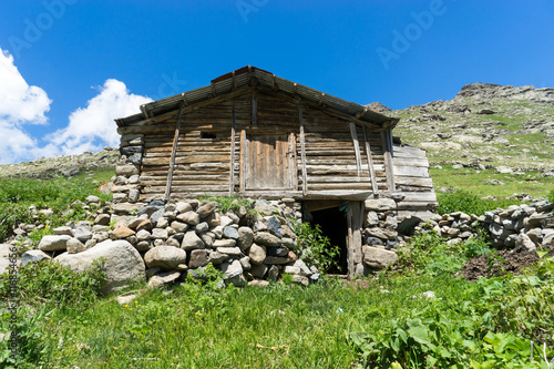 View of a wooden mountain cabin with mountains in the background