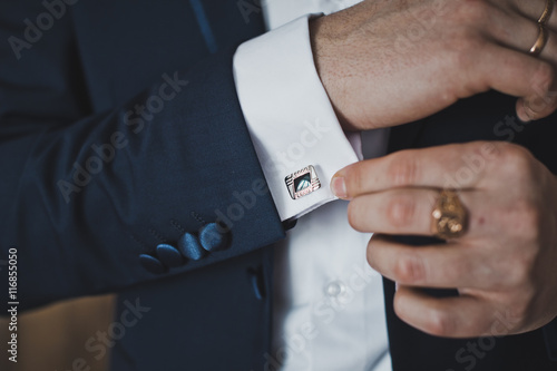 фотографія Putting on the cufflinks on the cuff of his shirt 6408.