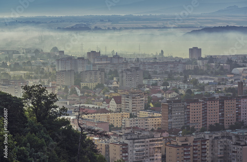 Aerial cityscape of residential districts and suburbs of the Brasov city, Romania, on a misty early morning.