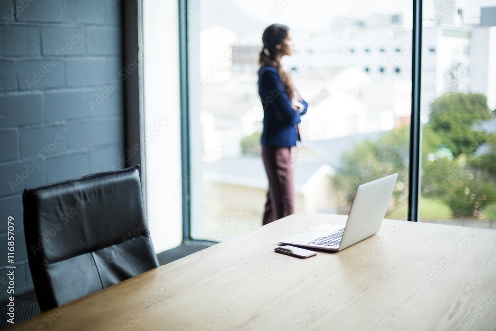 Woman standing at window in office Woman standing at window in office