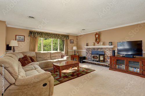 Living room in creamy tones with corner sofa and brick fireplace. © Iriana Shiyan