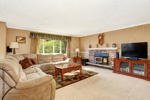 Living room in creamy tones with corner sofa and brick fireplace © Iriana Shiyan