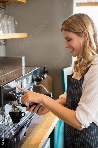 Smiling waitress making cup of coffee