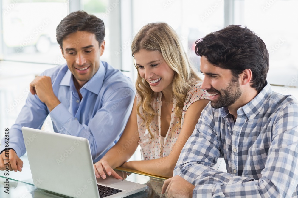 Smiling woman and two men using laptop