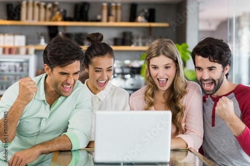 Group of excited friends using laptop