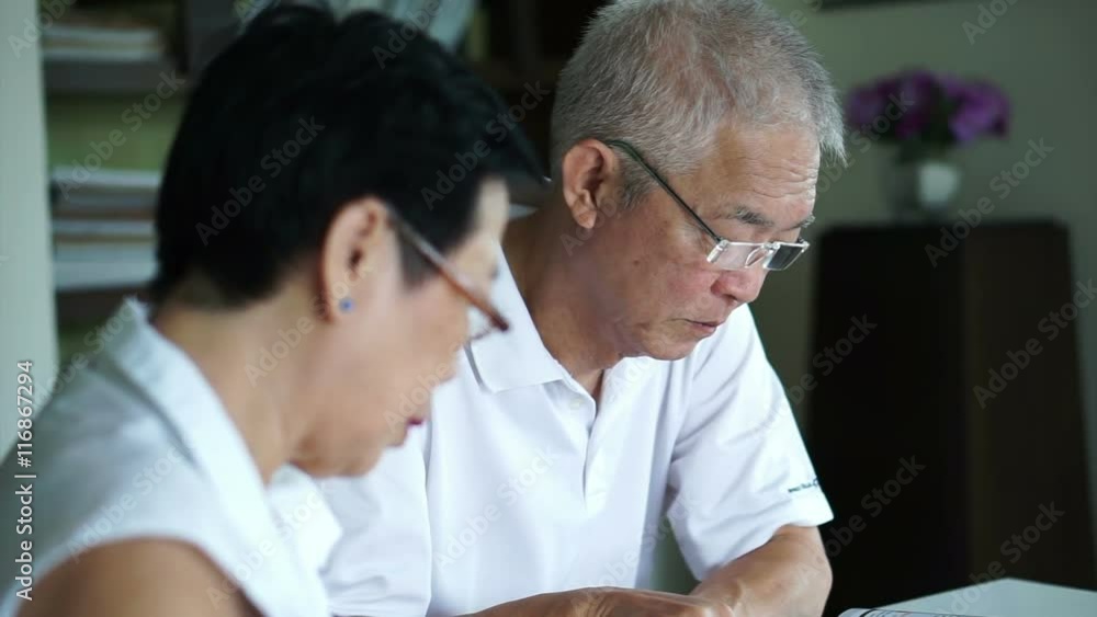 Asian senior couple reading books and magazines together in small library. Learning and study concept Asian senior couple reading books and magazines together in small library. Learning and study concept