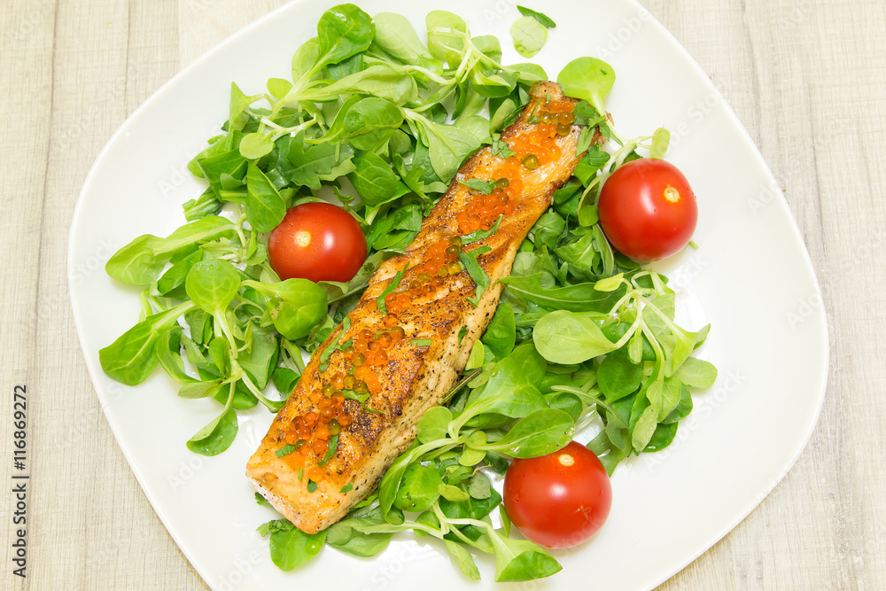 Roasted salmon with roots and tomatoes on a white plate Roasted salmon with roots and tomatoes on a white plate