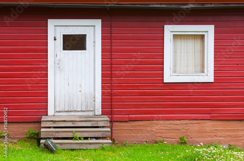 White closed door and window in red wall © evannovostro