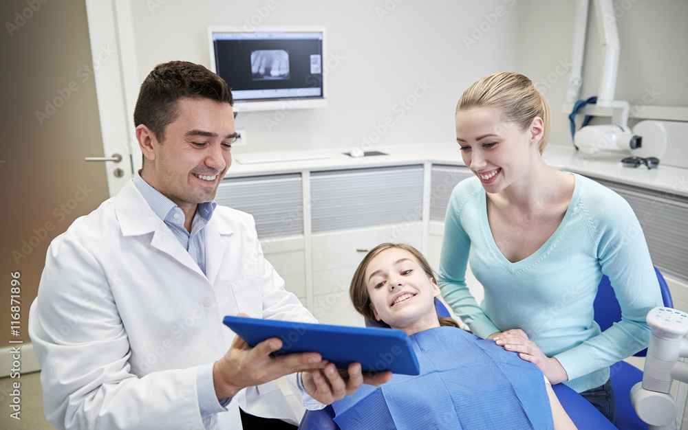 Obraz premium dentist showing tablet pc to girl and her mother