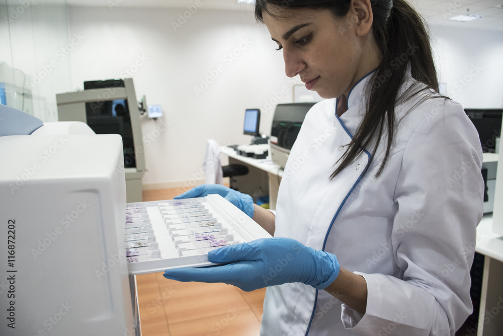 Laboratory technician in analytical laboratory putting object plates in cytology reader Laboratory technician in analytical laboratory putting object plates in cytology reader