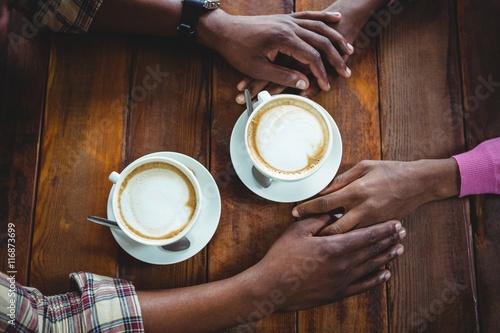 Couple holding hands while having coffee