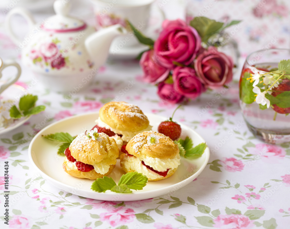 Cream puff cakes or profiterole filled with whipped cream,g served with strawberries Cream puff cakes or profiterole filled with whipped cream,g served with strawberries