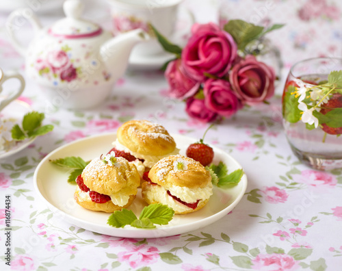 Cream puff cakes or profiterole filled with whipped cream,g served with strawberries