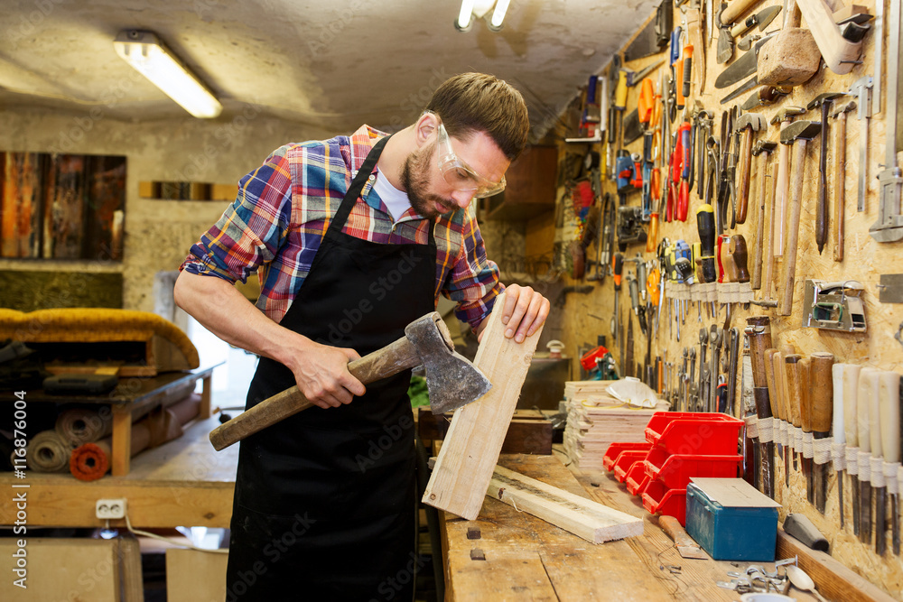 Fototapeta premium carpenter with ax and board working at workshop