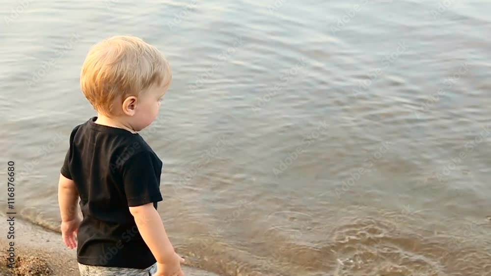 gay boy kid blonde throws a large stone into the water gay boy kid blonde throws a large stone into the water