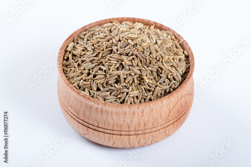 Cumin seeds or caraway in a wooden bowl isolated on white background