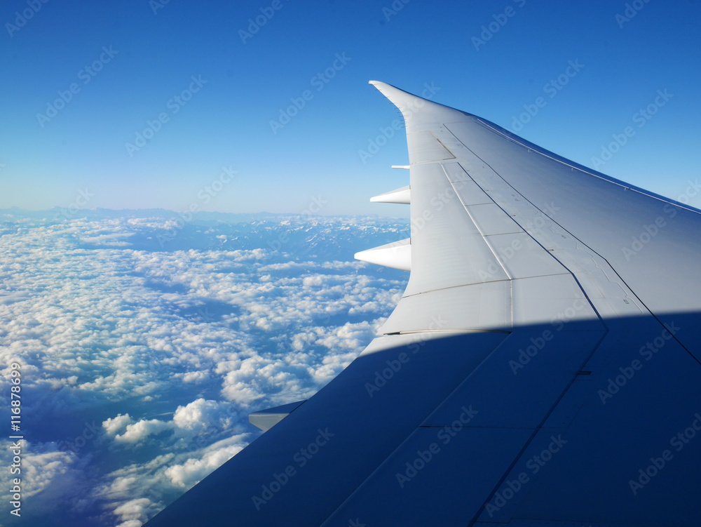 Plane wing and blue sky with beautiful clouds underneath and mou Plane wing and blue sky with beautiful clouds underneath and mou