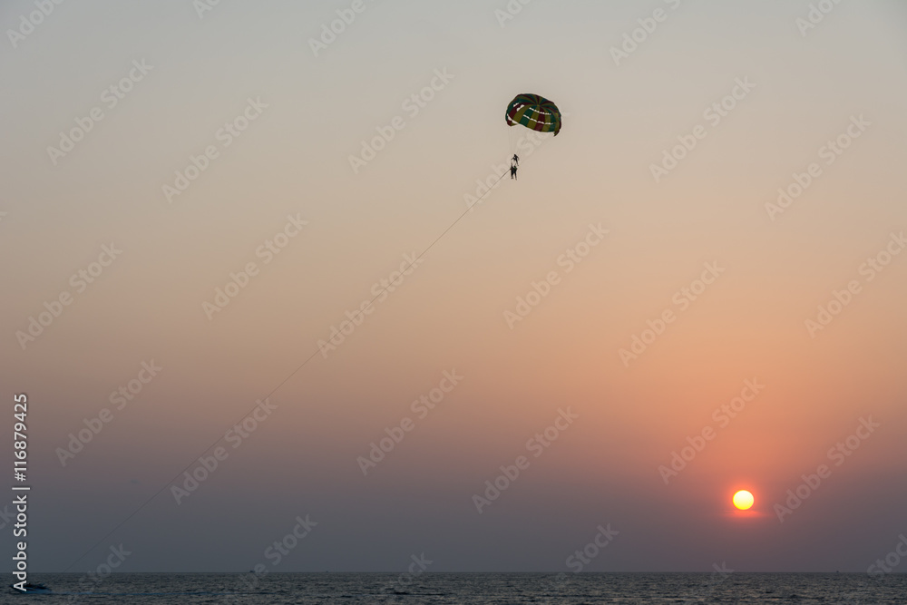 Silhouette of tourist playing parasailing during sunset Silhouette of tourist playing parasailing during sunset