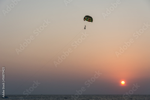 Silhouette of tourist playing parasailing during sunset