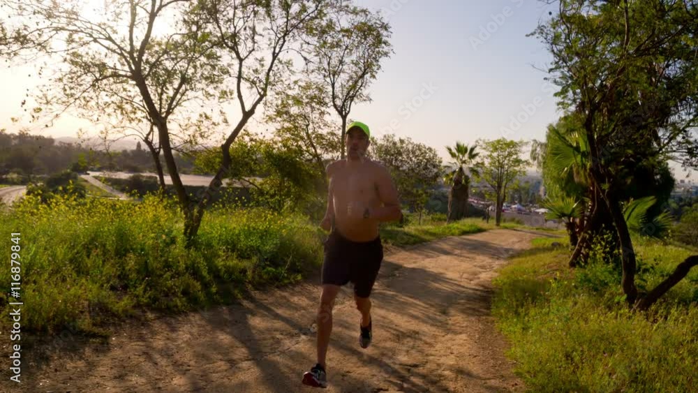 Athletic male jogging down a gravel trail. Slow Motion. Athletic male jogging down a gravel trail. Slow Motion.
