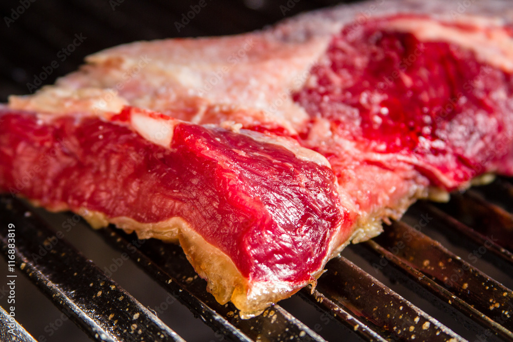 Raw meat with grease on metal grill
