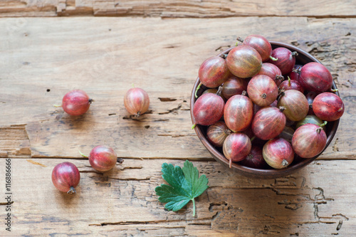 Ripe red gooseberryes in a clay bowl photo