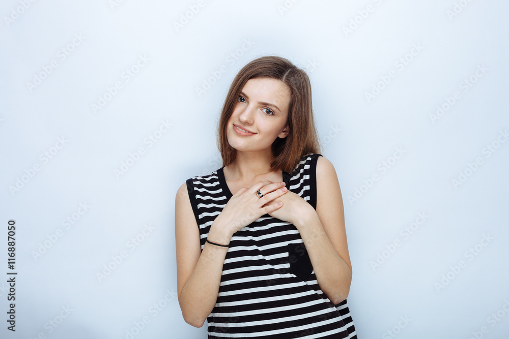 Portrait of happy young beautiful woman in striped shirt touching her neck posing for model tests against studio background Portrait of happy young beautiful woman in striped shirt touching her neck posing for model tests against studio background
