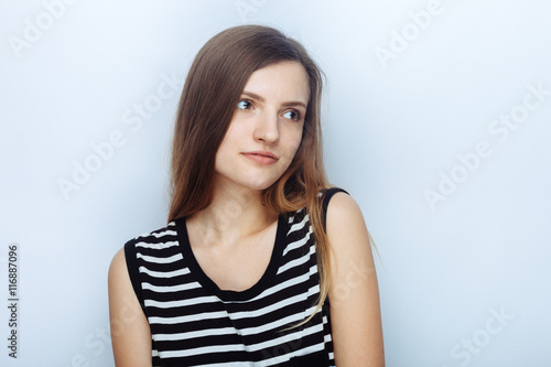 Portrait of happy young beautiful woman in striped shirt posing for model tests against studio background