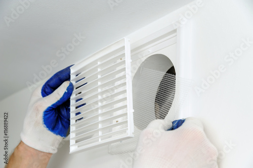 Cuadro en lienzo Worker installs ventilation grille.