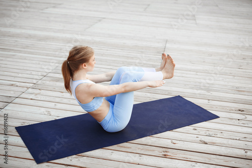 Young beautiful blonde girl practicing yoga outside. 