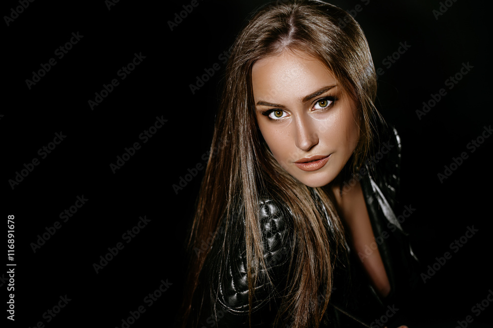 beautiful sexy brunette girl with long hair and big boobs. in the studio on a black background. Dressed in black jeans black leather jackets. girl in the image of rocker and biker. Advertising Space