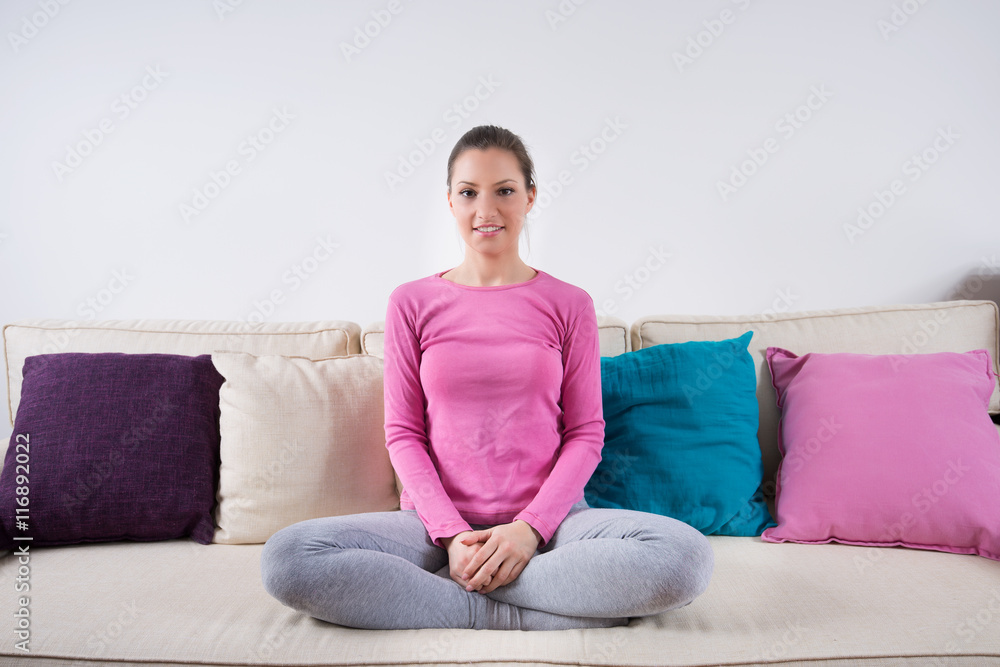 Young girl in yoga outfit seating on a couch and smiling Young girl in yoga outfit seating on a couch and smiling