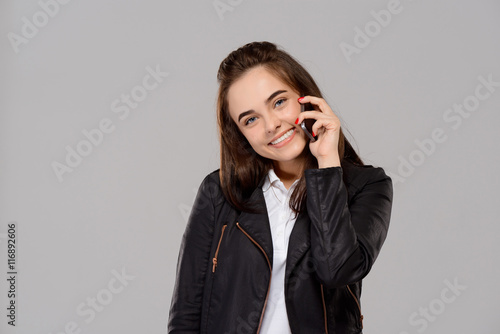 Young beautiful girl speaking on phone, smiling over purple background. 