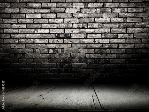 Dark room with wooden floor and brick wall background.