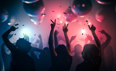Young happy people are dancing in club. Nightlife and disco concept.
