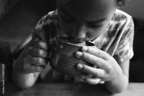 Child drinking from cup, black and white 