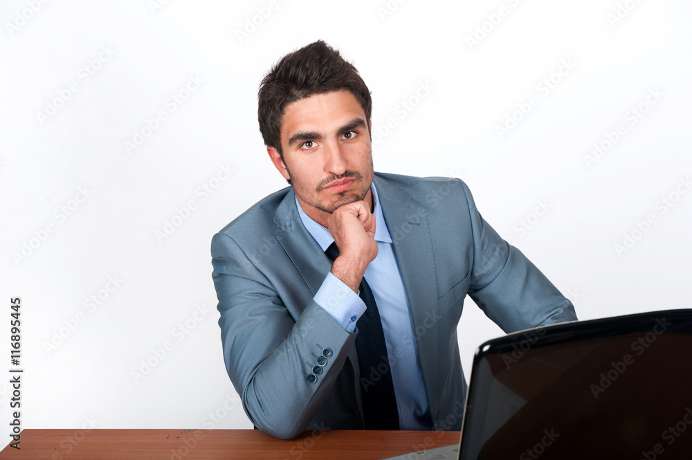 Young businessman sitting at his desk with a laptop Young businessman sitting at his desk with a laptop