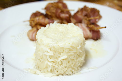 Rice with Rolls of slices of cooked bacon subject with a toothpi
