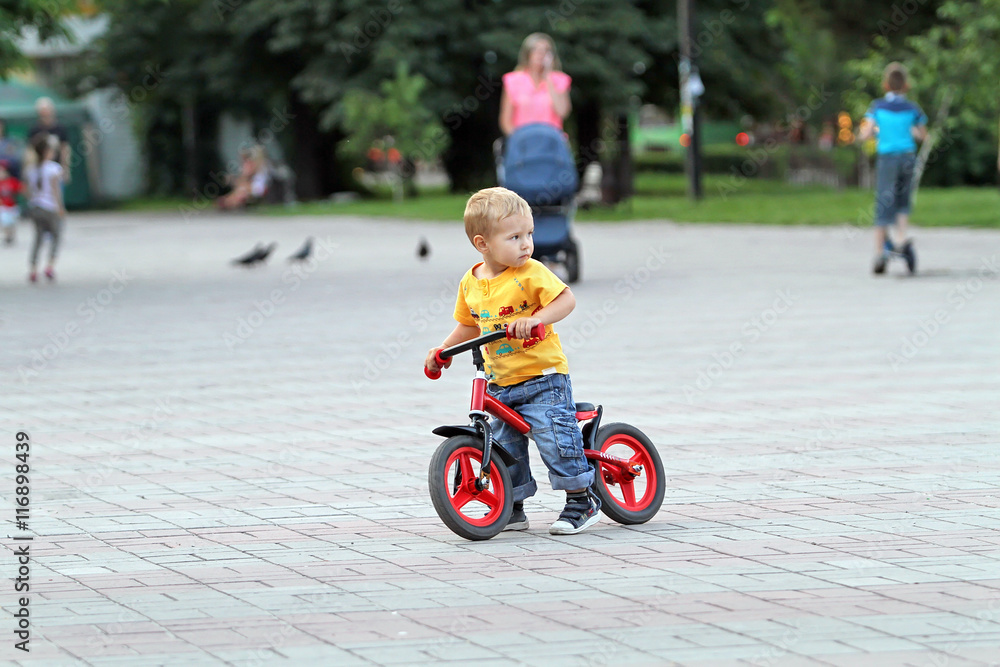 The small white boy with blond hair and blue jeans is riding on The small white boy with blond hair and blue jeans is riding on