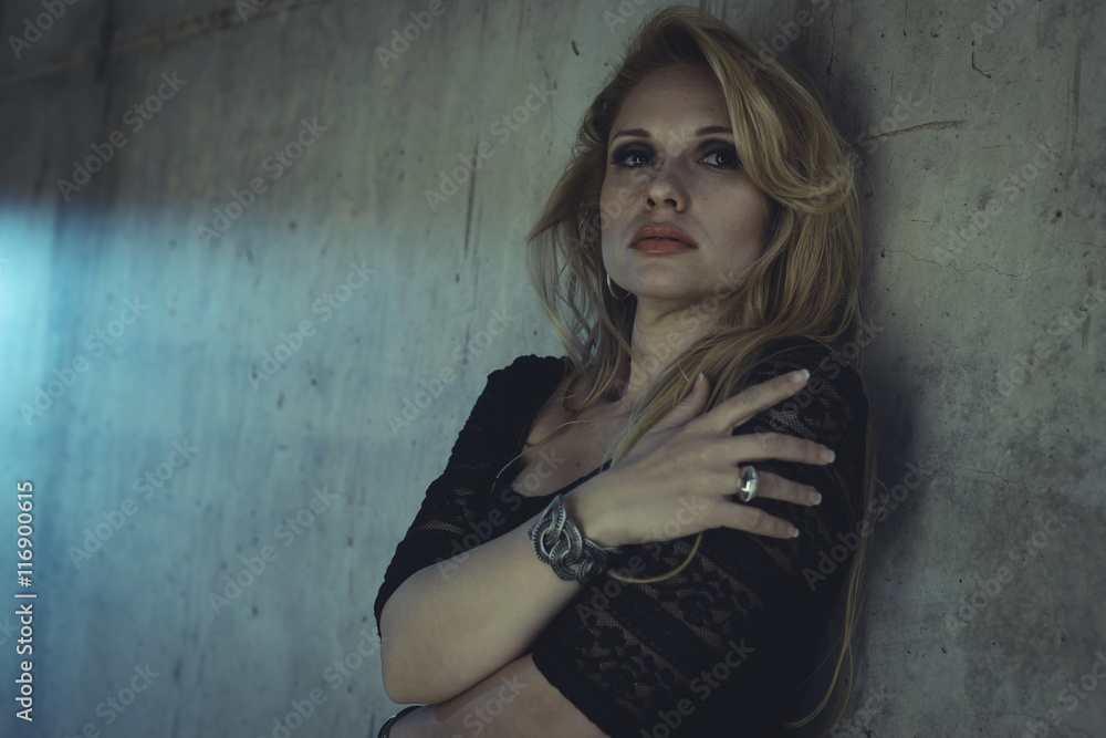 blonde dressed in skintight black costume on a gray cement wall blonde dressed in skintight black costume on a gray cement wall