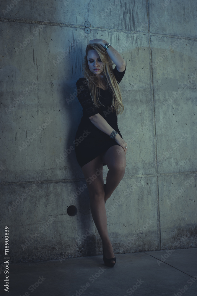 Fototapeta premium blonde dressed in skintight black costume on a gray cement wall