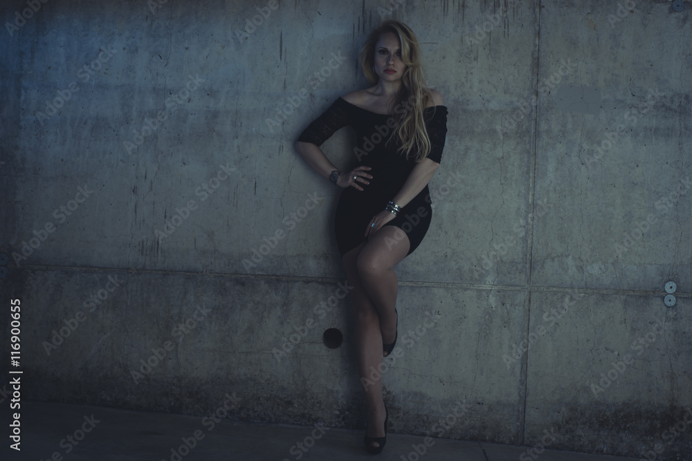 Fototapeta premium blonde dressed in skintight black costume on a gray cement wall