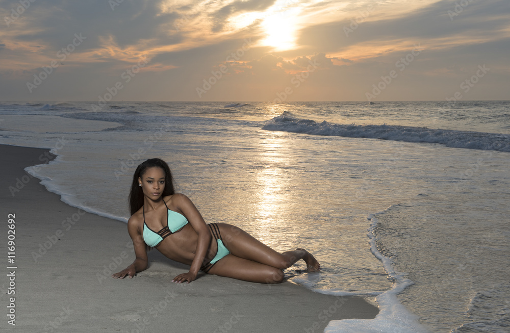 Beautiful African American female model posing on beach in swimsuit at  sunrise (sun rising behind her over ocean) - turquoise colored bikini Stock  Photo | Adobe Stock